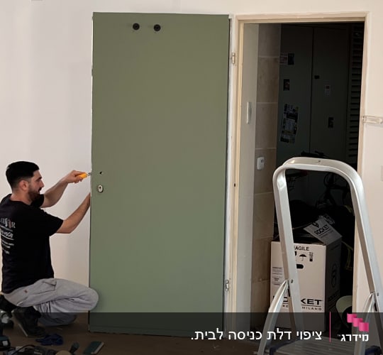 אדם מתקין דלת ירוקה עם כלים וסולם